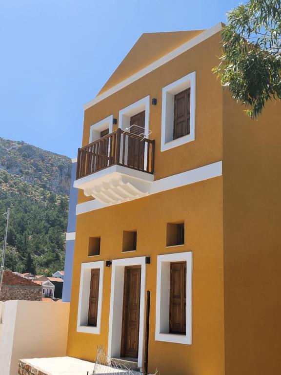 une maison jaune avec un balcon sur une colline dans l'établissement Kastello, à Megísti