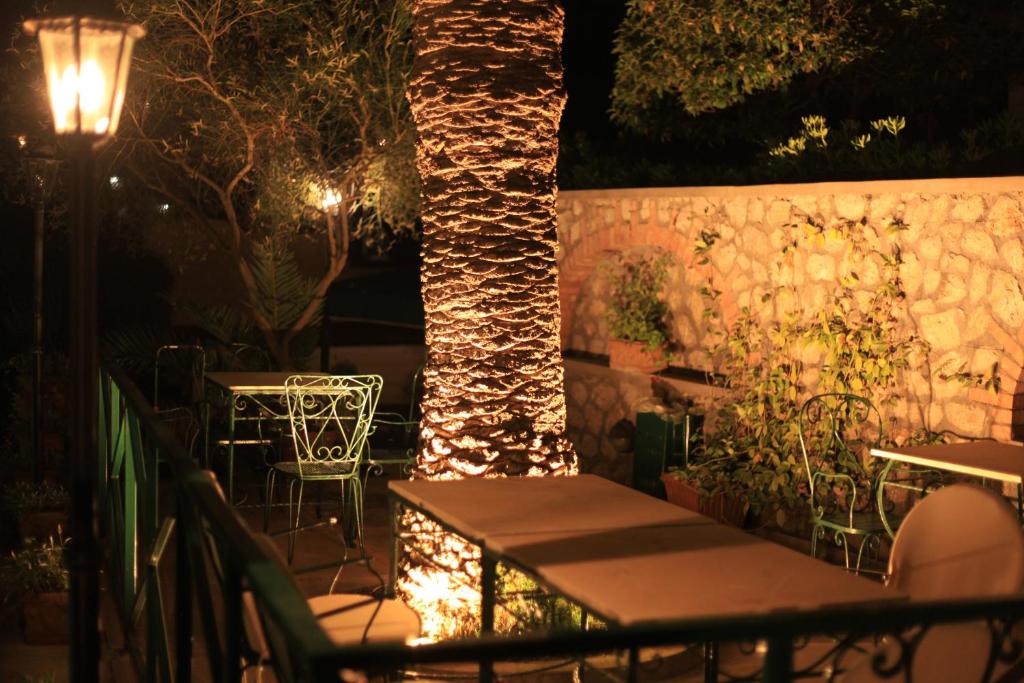 a patio with tables and a tree at night at Hotel Villa Sarah in Capri