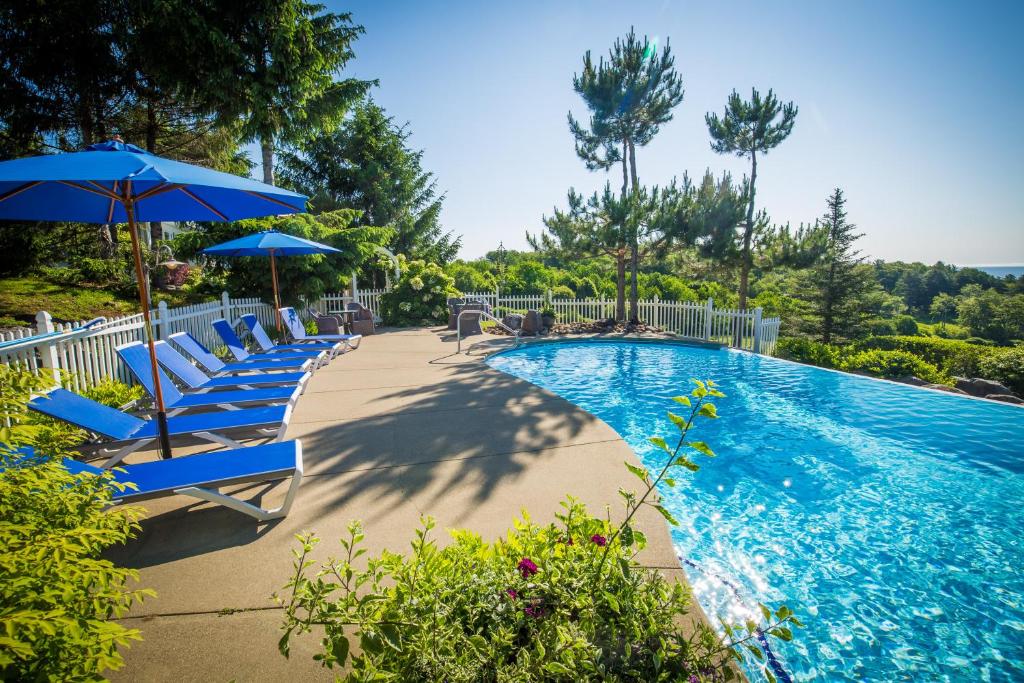 een zwembad met blauwe stoelen en parasols bij Island View Inn in Glen Cove