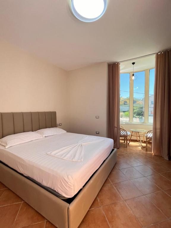 a bedroom with a bed and a large window at Belix Hotel Apartments, Near the Beach in Durrës