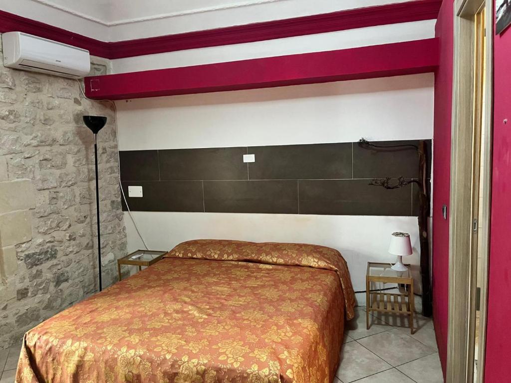 una camera con un letto con una parete rossa e bianca di Agora a Modica