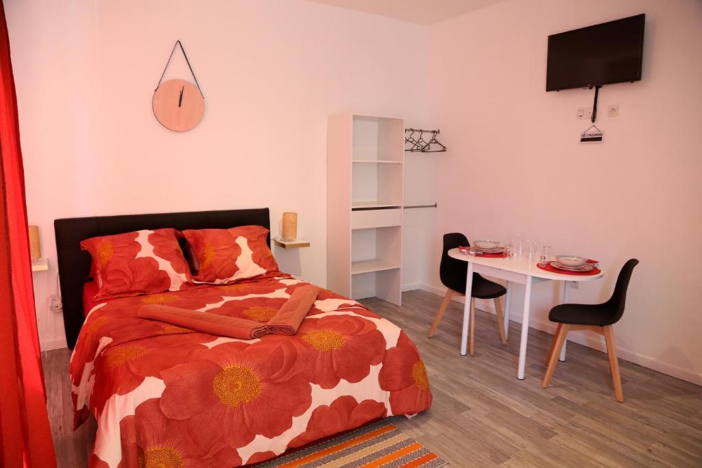 a bedroom with a bed and a table with a chair at Saturne in Saint-Quentin