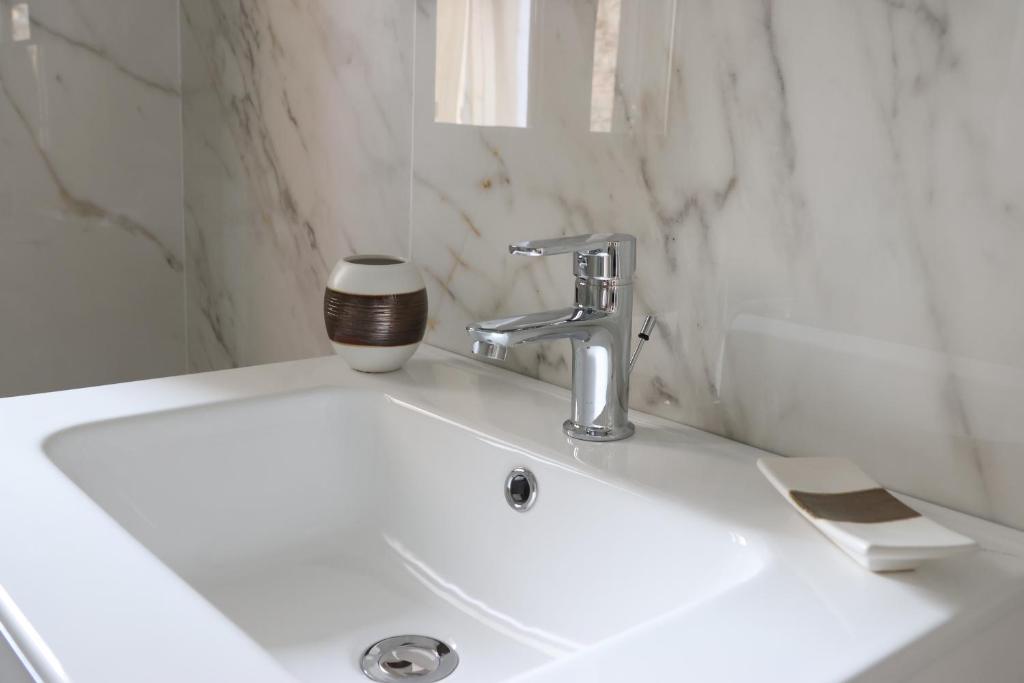 un lavandino bianco del bagno con una tazza di caffè di Il Borgo civ.15 a Paola