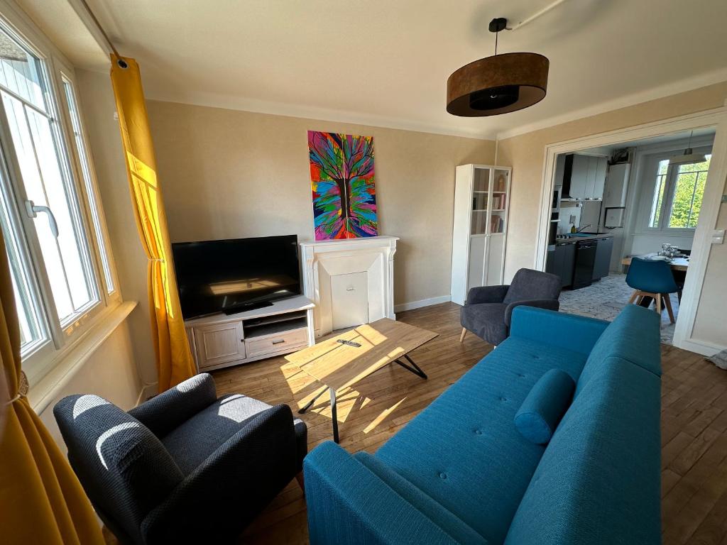 a living room with a blue couch and a tv at Chez Tante Muguette proche Dinan in Le Hinglé