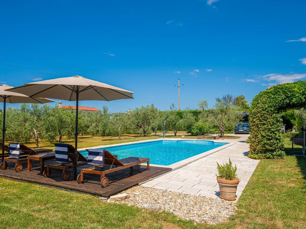 una piscina con 2 sillas y una sombrilla en Villa Benka, Istrian stone house en Tinjan