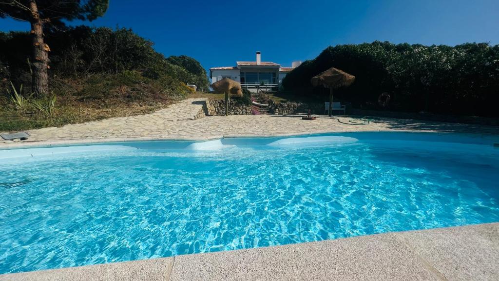 a large blue swimming pool next to a beach at Lovely Beach House with Stunning View in Sesimbra
