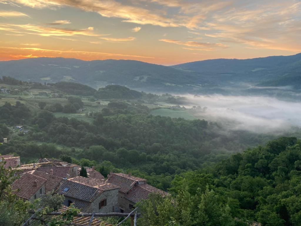 vista su un villaggio in collina con nebbia di Casa di pietra a Castelnuovo di Val di Cecina