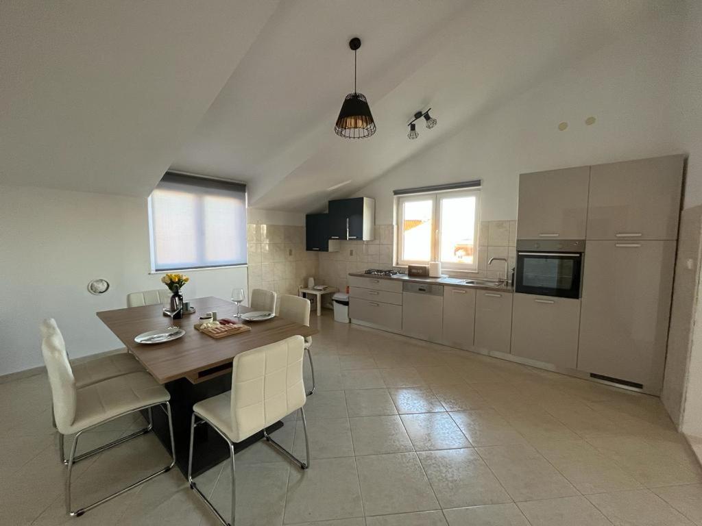 a kitchen with a wooden table and white chairs at Apartments Majić in Kaštela