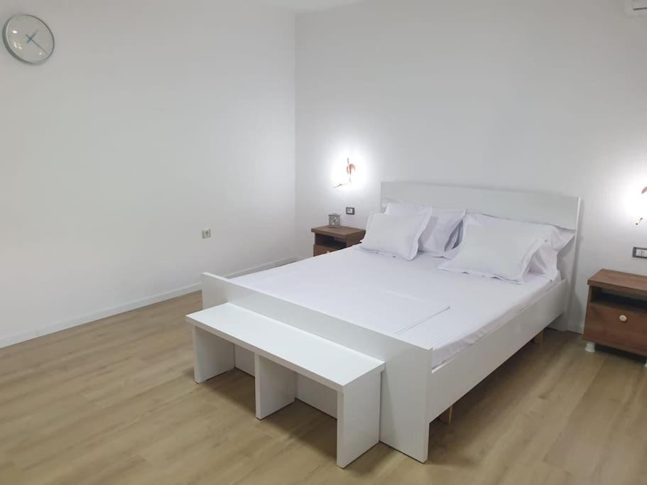 a white bedroom with a white bed and a table at Center Lake House in Shkodër