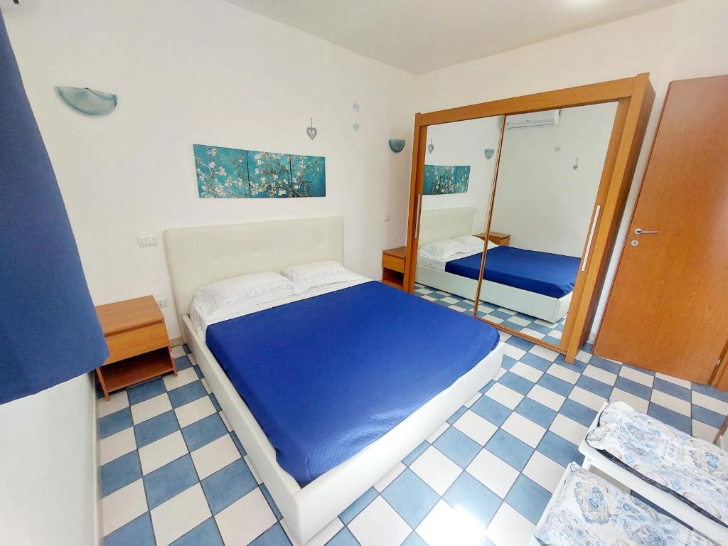 1 dormitorio con cama azul y espejo en Casa di Agnese, en Alghero