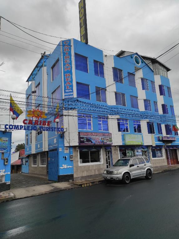 un edificio azul con un coche aparcado delante de él en HOTEL CARIBEAN REAL, en Latacunga