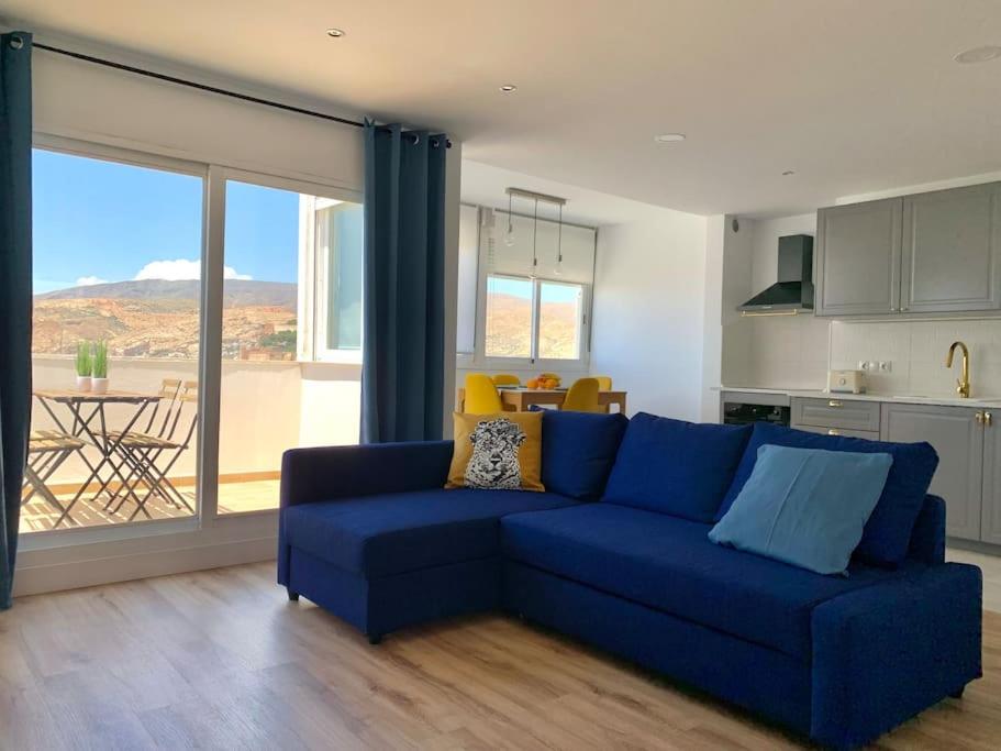 un sofá azul en una sala de estar con cocina en ATICO PASEO DE ALMERÍA en Almería