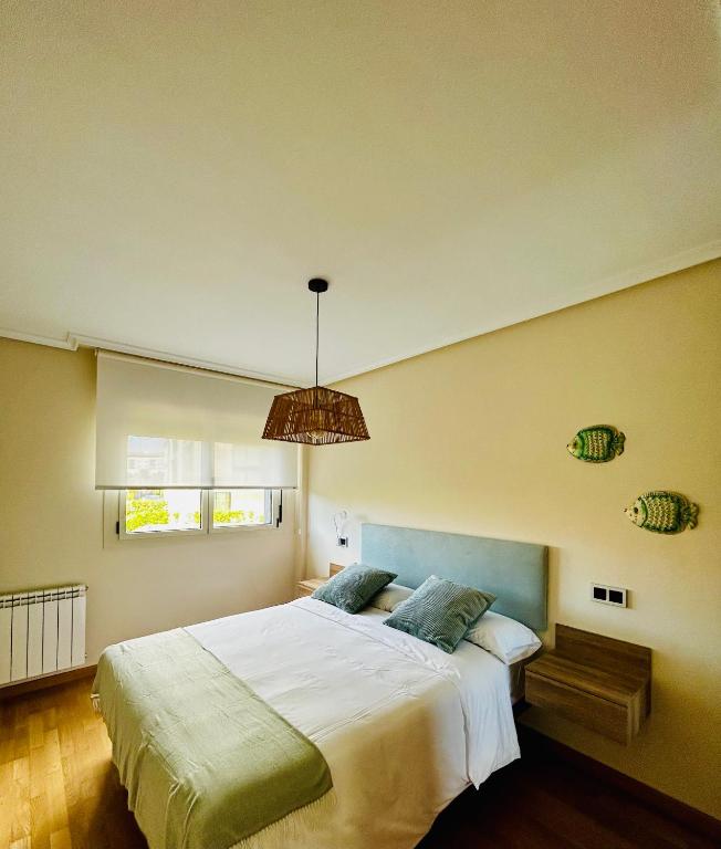 a bedroom with a large white bed and a window at MARINA LLANES V in Llanes