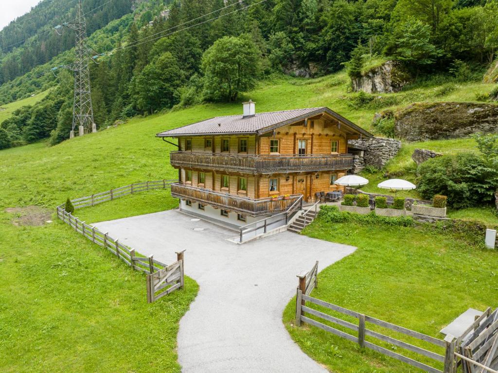 ein großes Holzhaus auf einem Hügel mit einem Zaun in der Unterkunft Schiestl's Landhaus in Mayrhofen