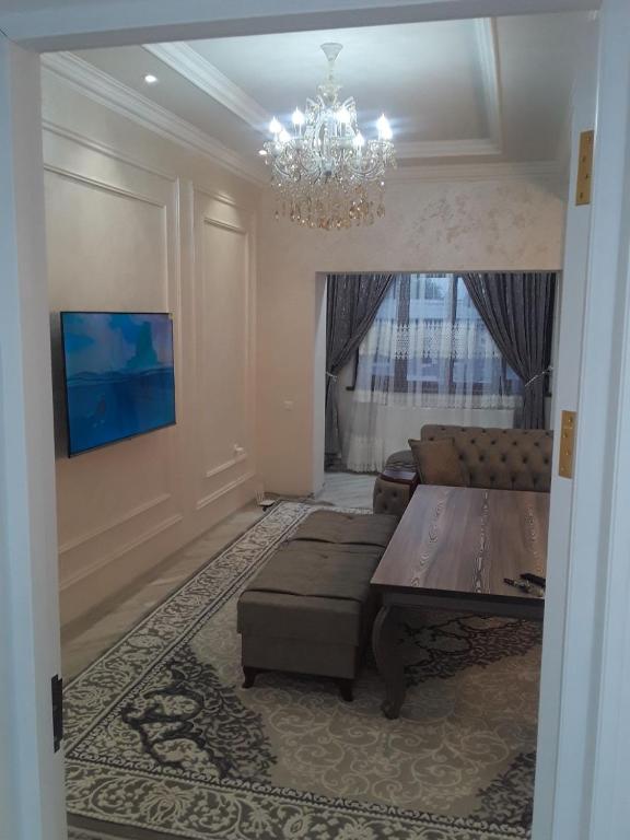 sala de estar con mesa y lámpara de araña en Apartment en Ferganá