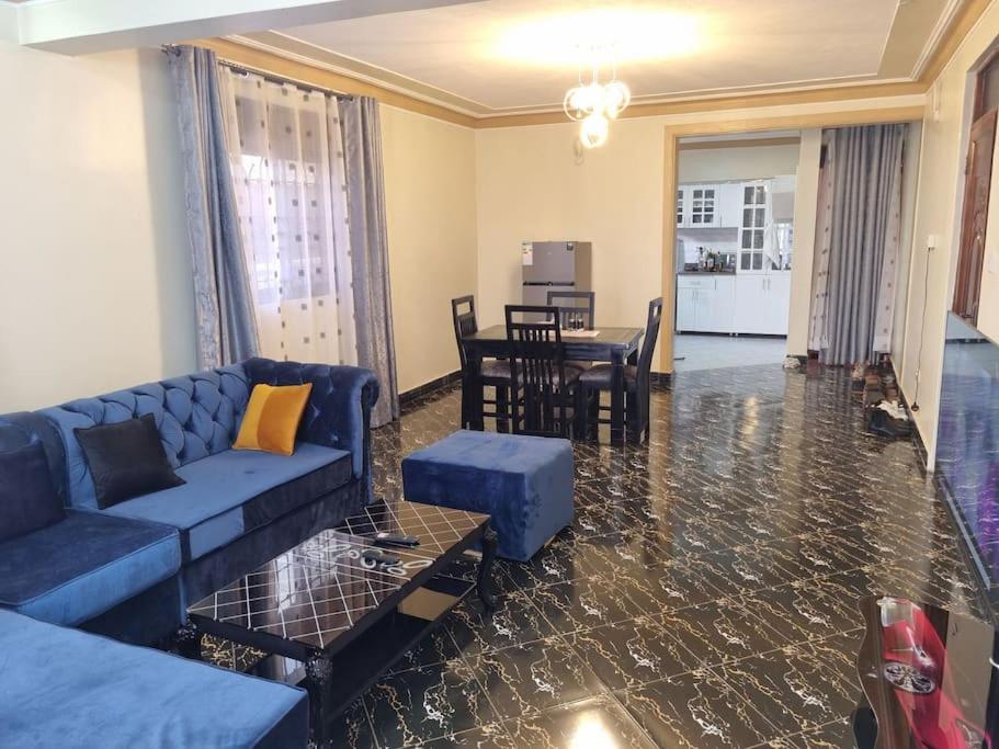 sala de estar con sofá azul y mesa en Lovely 2 _ bedroom unit, en Kampala
