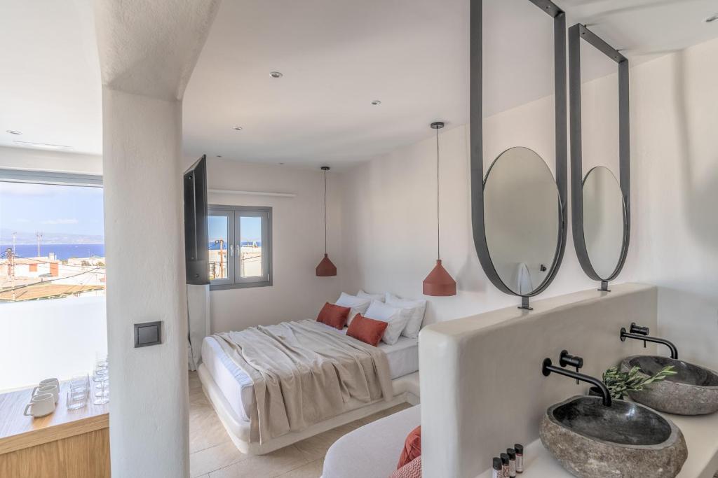 a bathroom with a bed and a sink and mirrors at Enalios sunset suites in Naxos Chora