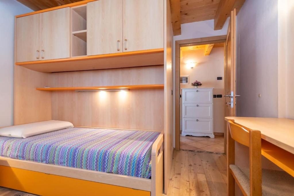 een kleine slaapkamer met een bed en een bureau bij Appartamento Mazzini in Predazzo
