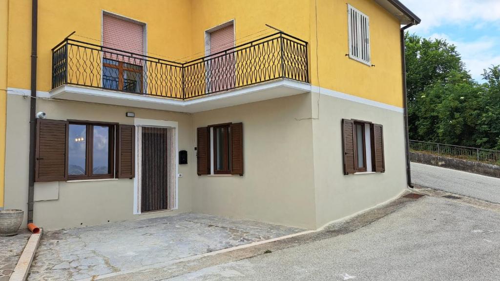 een geel en wit huis met een balkon bij B&B Casa Vacanza Greci in Greci