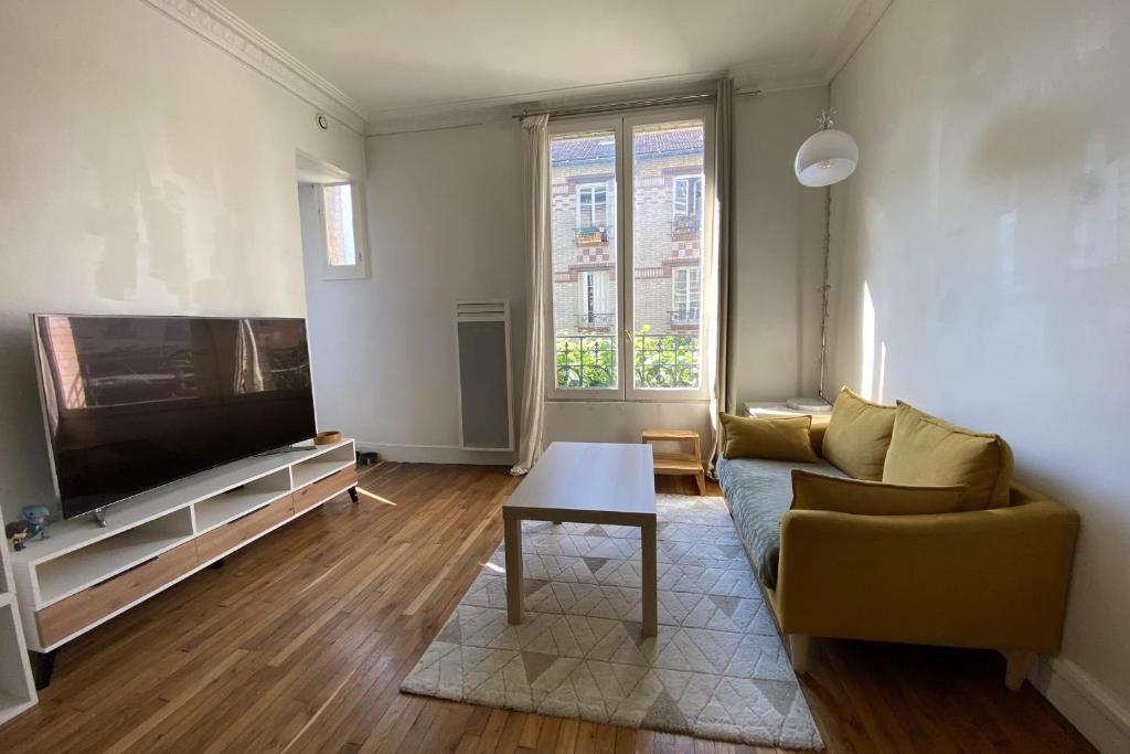 een woonkamer met een bank en een tv bij Cozy love nest near the Seine in Issy-les-Moulineaux