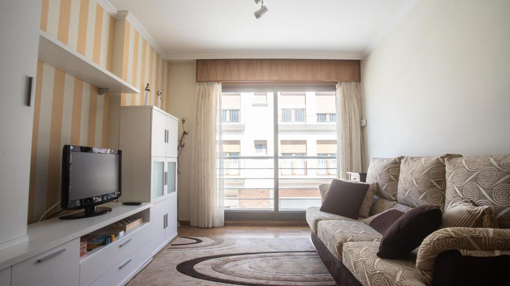 uma sala de estar com um sofá e uma televisão em Apartamento en el centro con plaza de garaje em A Guarda