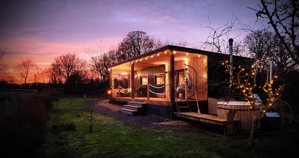 a tiny house with lights on it in a yard at Bastle Retreats Cabin with hot tub in Duns