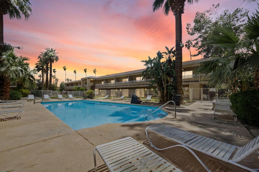 a resort swimming pool with lounge chairs and palm trees at Sol Springs Inn in Palm Springs