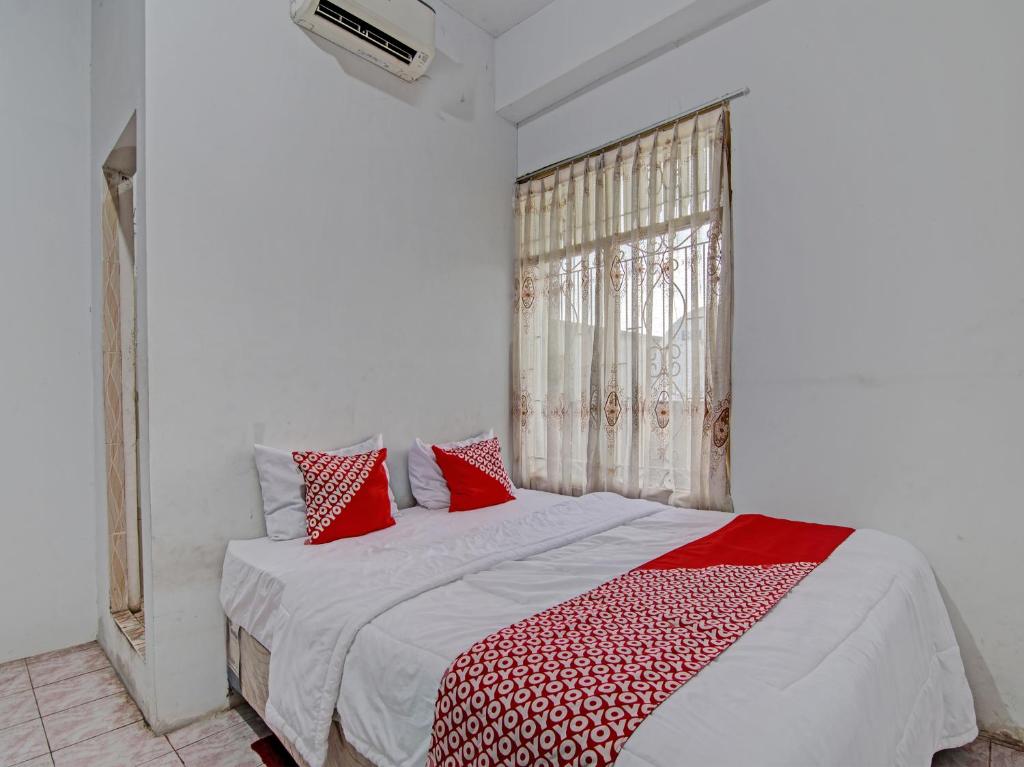 - une chambre avec un lit doté d'oreillers rouges et blancs dans l'établissement OYO 92746 Wisma 35, 