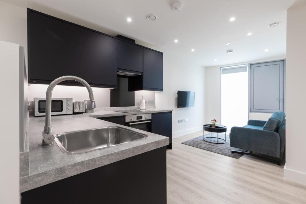 a kitchen with a stainless steel sink and a living room at StayInn Stratford in London