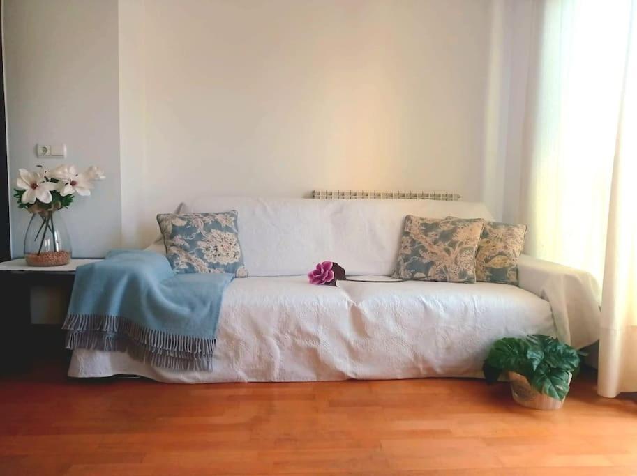- un canapé blanc avec des oreillers dans le salon dans l'établissement Acogedor apartamento con piscina y garaje, à Huesca