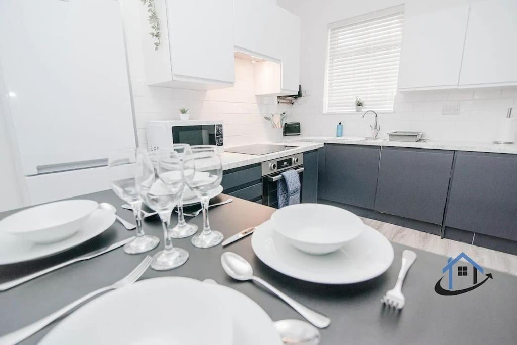 a kitchen with a table with plates and glasses on it at Balby Casa king beds parking workspace wifi corporates pets in Balby
