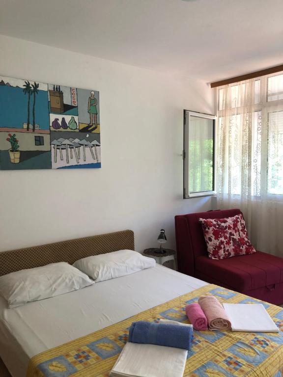 a bedroom with two beds and a red chair at Ćetković 1 in Petrovac na Moru