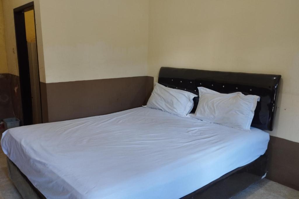 1 dormitorio con 1 cama con sábanas y almohadas blancas en OYO 92756 Kos Moncok en Tjakranegara