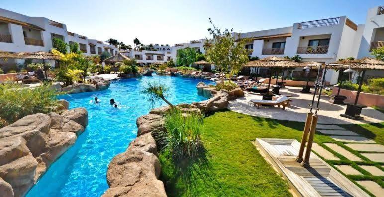 a swimming pool in a resort with people in it at Appartamento Elisir Domina Coral Bay in Sharm El Sheikh