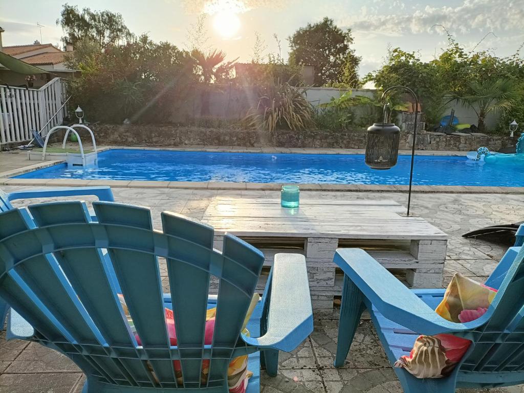 um pátio com uma mesa e cadeiras ao lado de uma piscina em Les Bichettes em Mortagne-sur-Sèvre