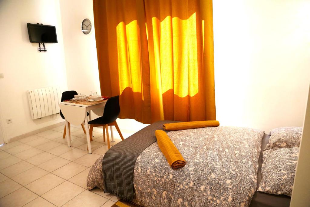 Schlafzimmer mit einem Bett und einem Tisch sowie gelben Vorhängen in der Unterkunft MERCURE in Saint-Quentin