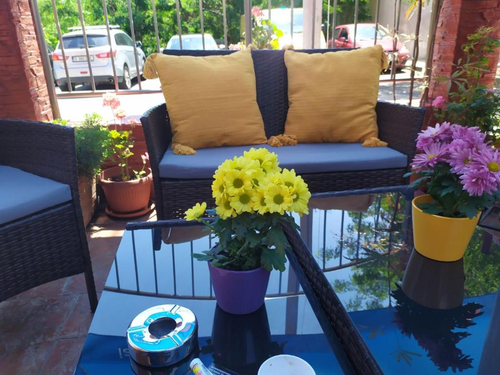 a couch on a balcony with flowers on a table at Adri Guest House in Nesebar
