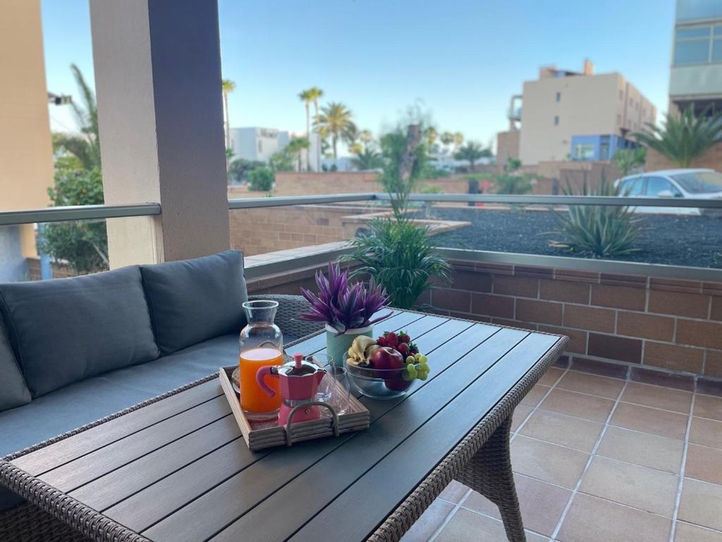 ein Tablett mit Obst und Saft auf einem Tisch auf einem Balkon in der Unterkunft Apartamento Kai in Playa Jandia