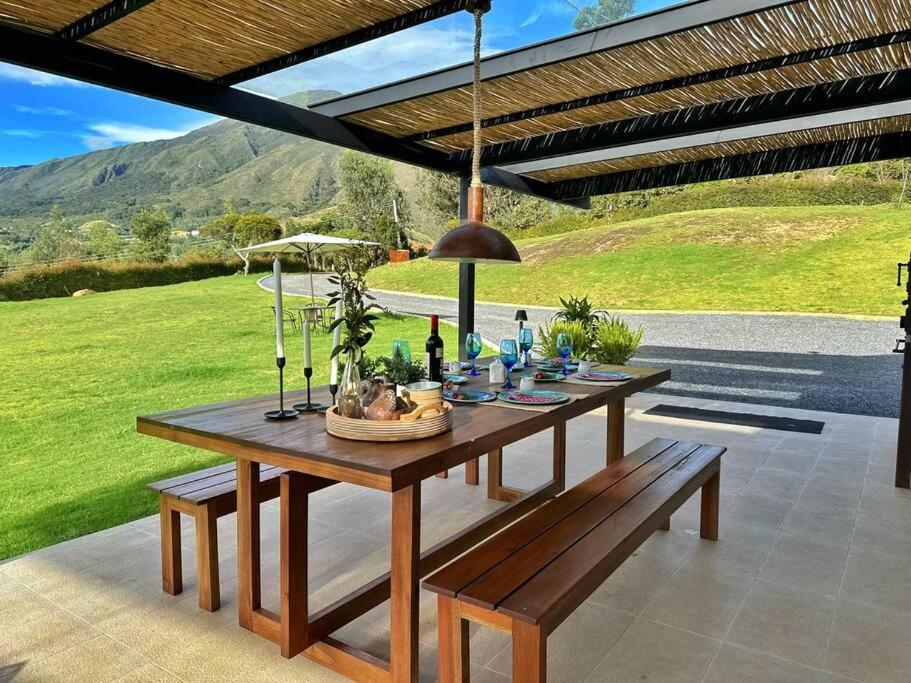 een houten tafel en banken op een patio bij Casa Araní - Vista espectacular y mucho jardín in Villa de Leyva