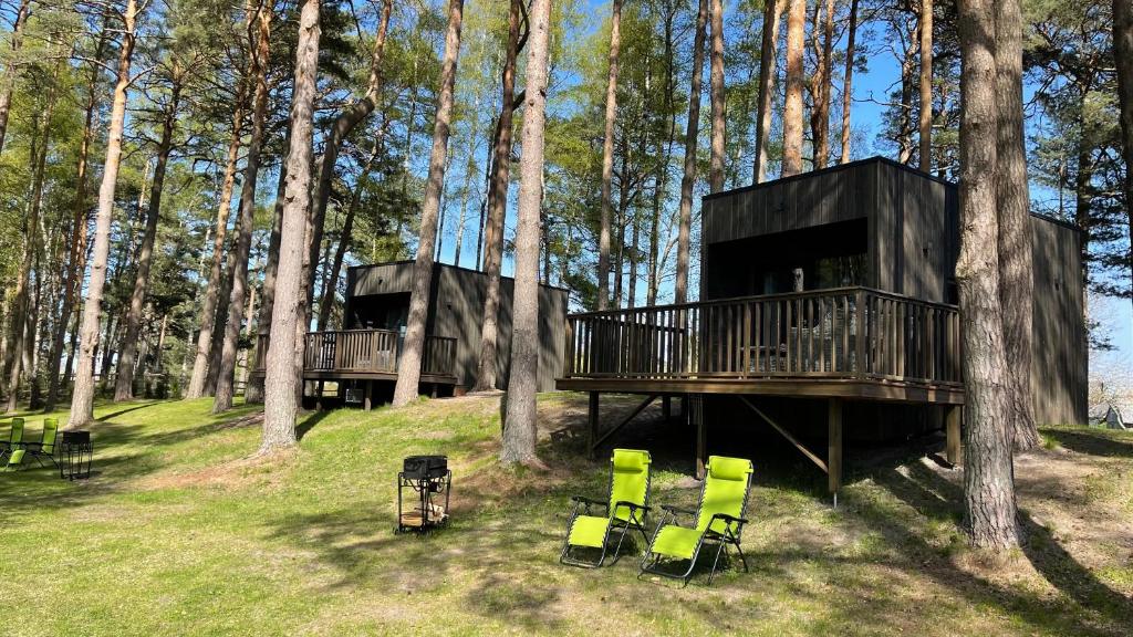 a couple of chairs and a tree house in the woods at Little Amber in Bernāti