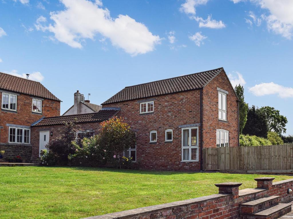 a large brick house with a grass yard at The Stables in Whissendine