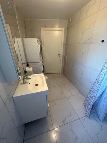 uma casa de banho branca com um lavatório e um espelho em Kulladal Malmö em Malmö