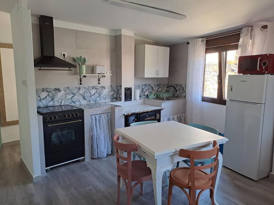 een keuken met een witte tafel en stoelen en een fornuis bij Casiña Flor do Maravillas Roblido in Roblido
