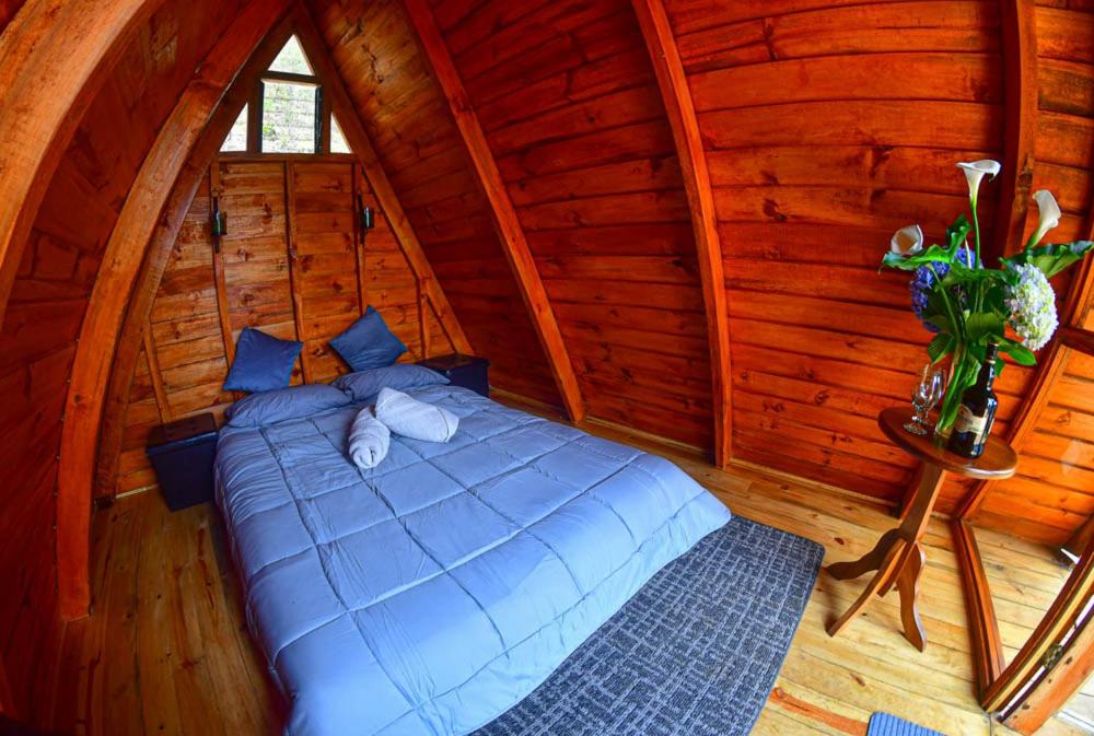 a bedroom with a bed in a log cabin at CANTOS DEL VIENTO in Desamparados