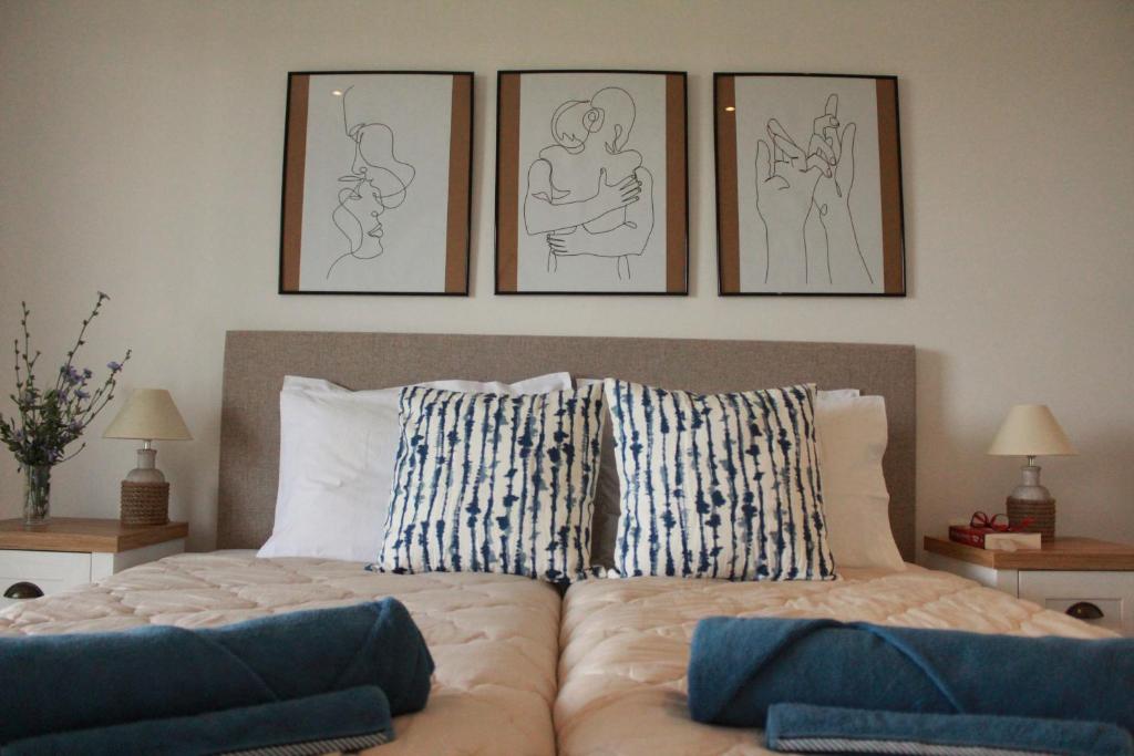 a bedroom with a bed with four drawings on the wall at Vista Vibes Corfu in Análipsis