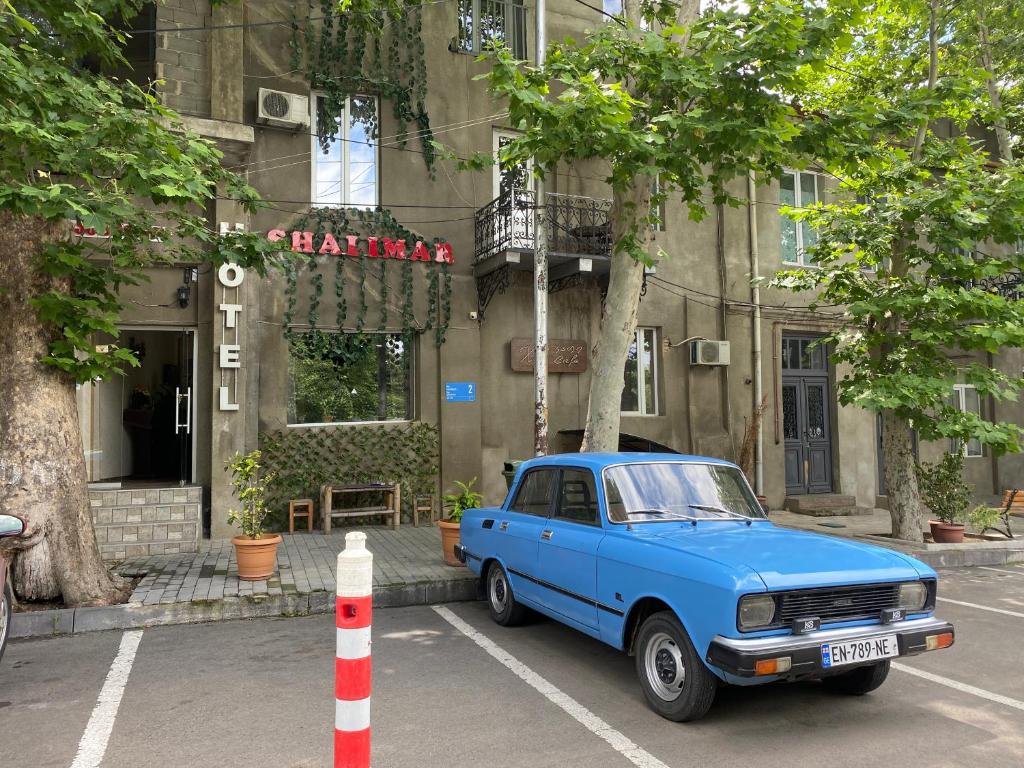 une voiture bleue garée devant un bâtiment dans l'établissement Hotel Shalimar, à Tbilissi