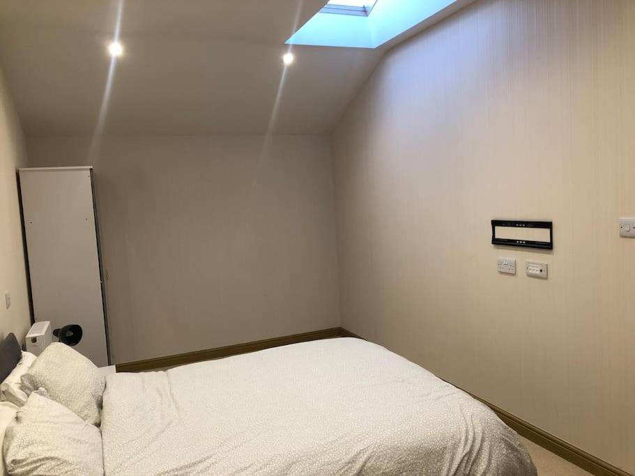 een kleine slaapkamer met een bed met een dakraam bij Flat in North Acton in Londen