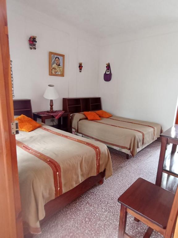 Habitación con 3 camas, mesa y silla en Hostal Mario's Rooms, en Panajachel