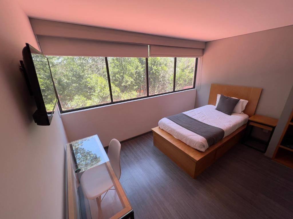 um pequeno quarto com uma cama e uma janela em Bonsai Las Aguilas em Cidade do México