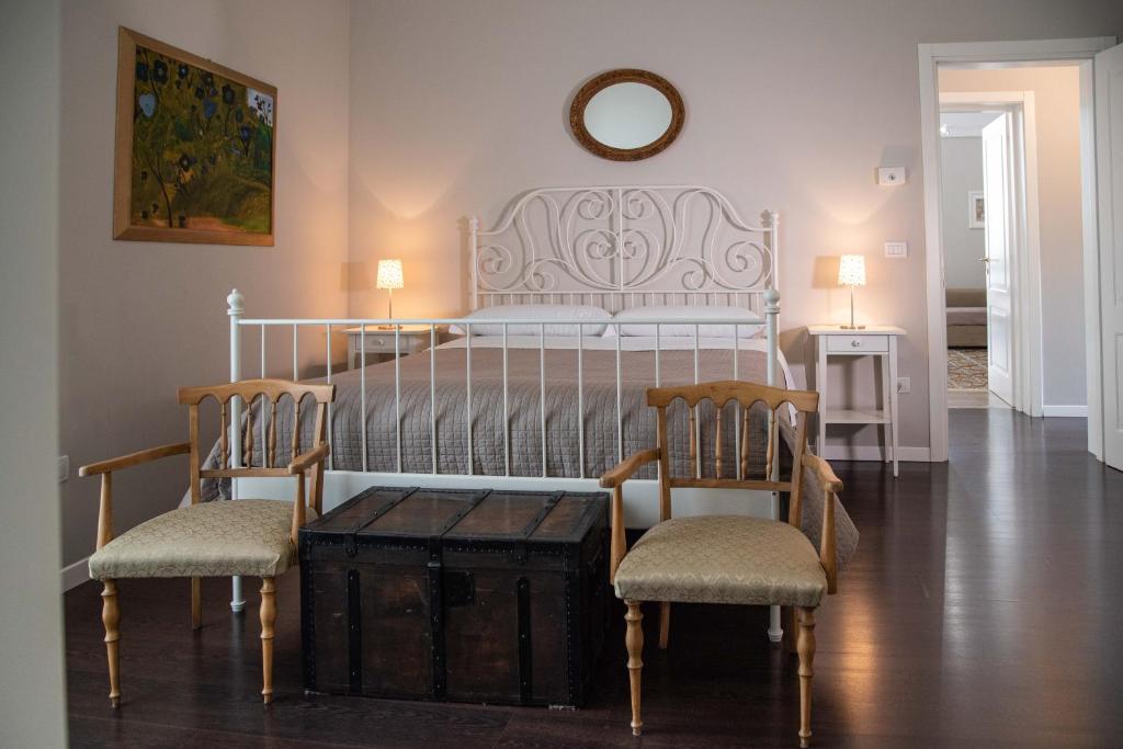 Dimora del Castellano في جويا ديل كولي: غرفة نوم بسرير ابيض مع كرسيين وطاولة